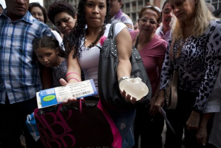 Anyoly Suarez holds, on one hand, her breast implants certificate and on the other a breast silicone implant, from the French brand Poly Implant Prothese, PIP, that was removed from her body because it was damaged, outside the civil court in Caracas, Venezuela, Friday, Jan. 6, 2012.  According to lawyer Emilia De Leon, around 400 women affected by breast implants made by PIP, filed Friday a request for an injunction against the implants' distributors in Venezuela. (AP Photo/Ariana Cubillos)